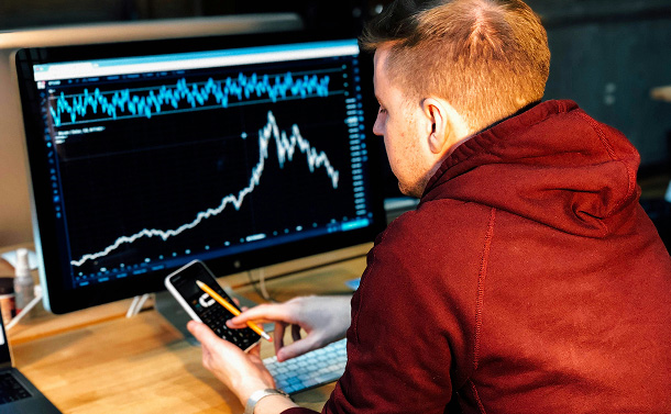 Man looking at graphs on desktop computer and phone