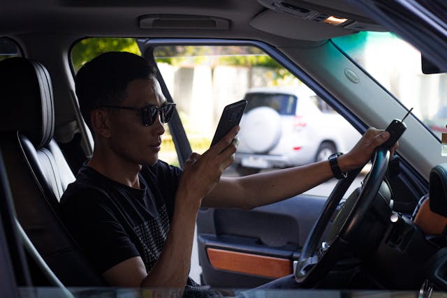 man wearing sunglasses in car looking at phone